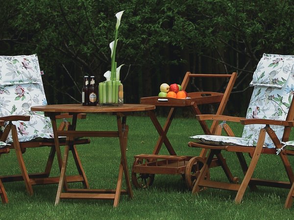 Floral pattern cushions on wooden folding garden chairs with side table