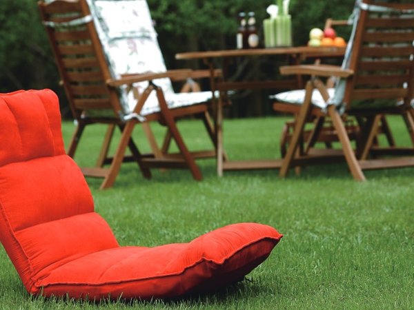 Red floor cushion chair with footrest on outdoor lawn