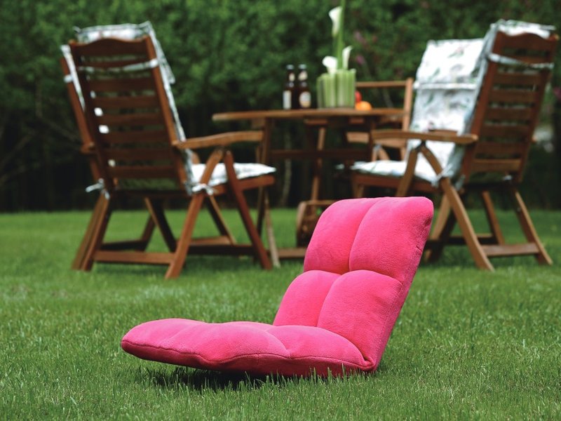 Bright pink segmented floor cushion chair on a green lawn