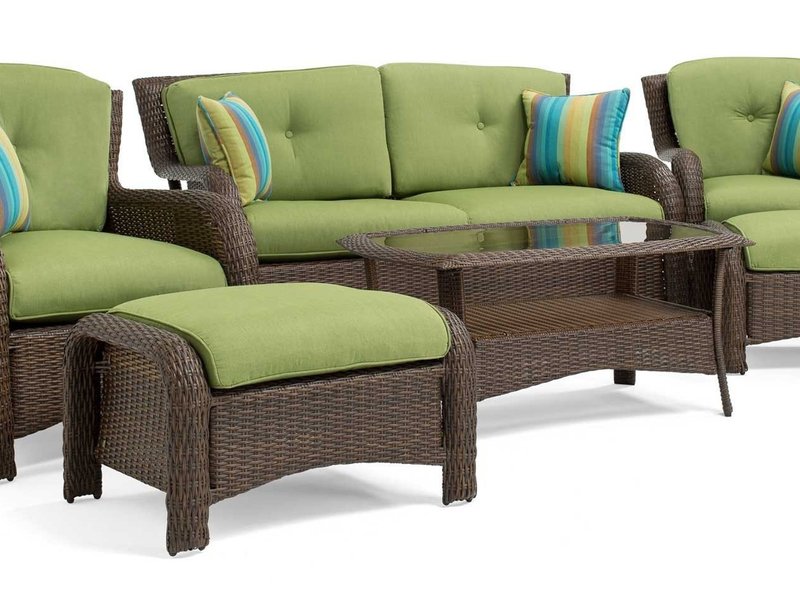 Complete wicker sofa set with green cushions, striped accent pillows and glass coffee table