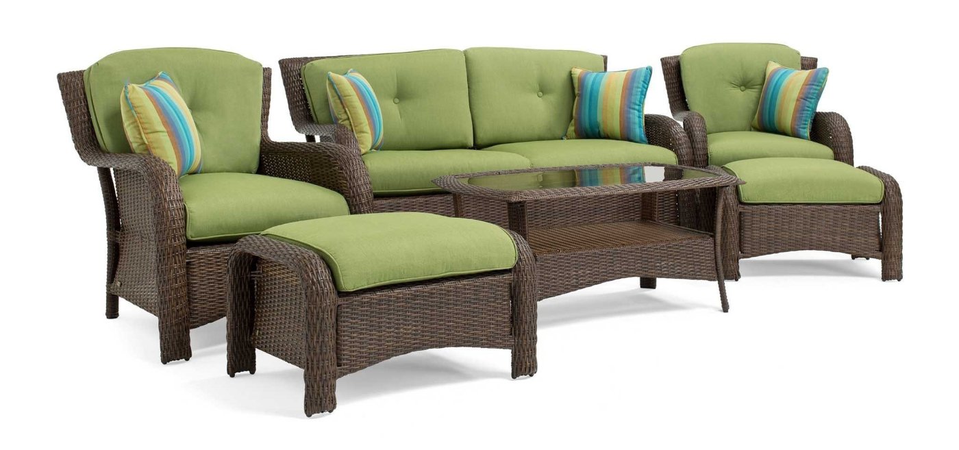 Gray wicker outdoor sofa set with green cushions and side tables